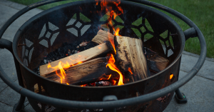 Traditional Wood Burning Firepit with Stacked Logs and Glowing Flames, Creating a Warm Outdoor Gathering Space